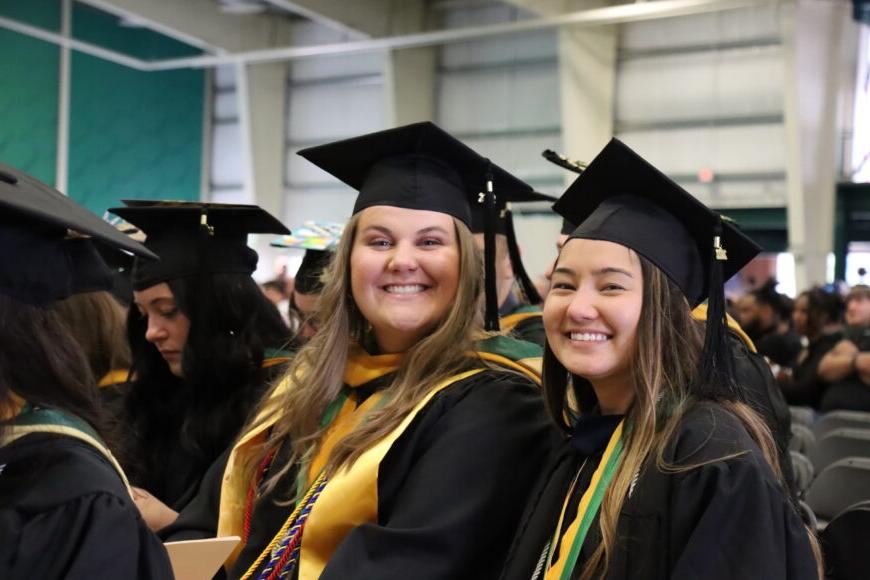 two smiling students at graduation